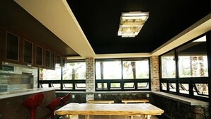 A modern kitchen with a large island, red bar stools, and large windows providing natural light. - Starlightdrops Pension (Jeju City)