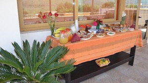 A buffet table with various food items and a vase of red roses. - Triskell Camere & Relax (San Vito Lo Capo)