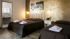 A hotel room with two beds, a bathroom with a large mirror, and a painting on the wall. - Triskell Camere & Relax (San Vito Lo Capo)