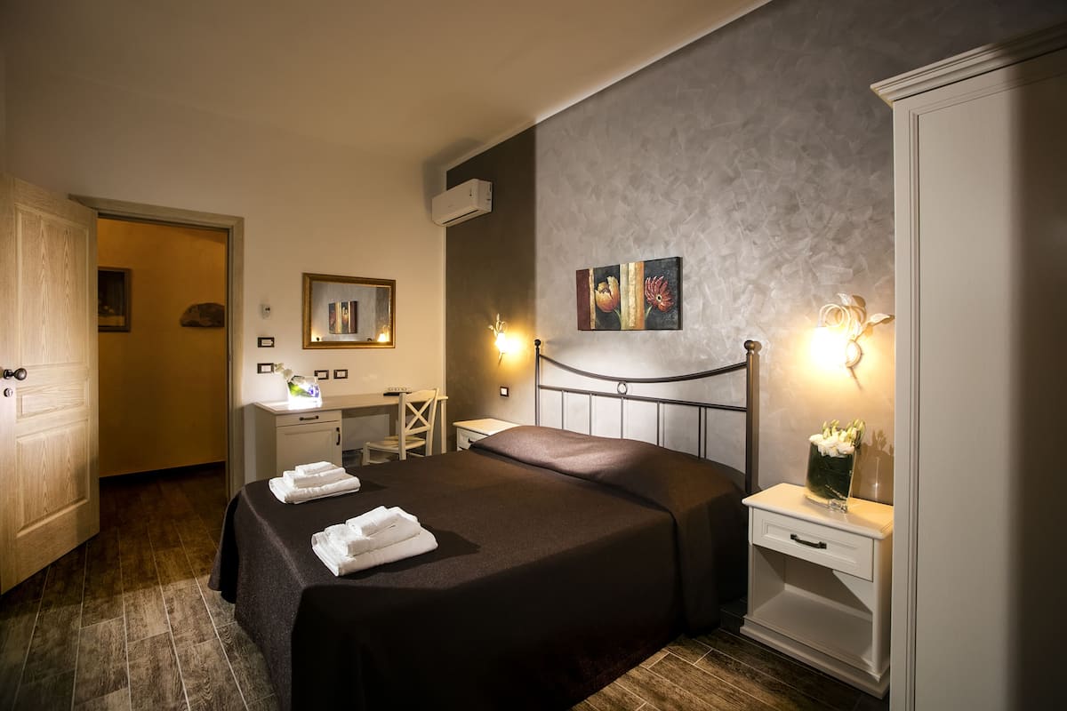 Habitación de hotel con cama, mesita de noche y escritorio con silla.