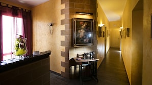 A hallway with a stone accent wall, a painting, a sewing machine, and a vase with flowers. - Triskell Camere & Relax (San Vito Lo Capo)