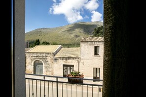 A view from a balcony with a mountain in the background, a building with a tiled roof, and a potted plant on the balcony. - Triskell Camere & Relax (San Vito Lo Capo)
