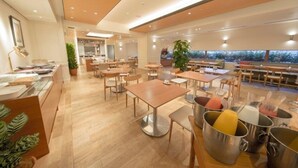 Un restaurant moderne avec un plancher en bois, des tables et des chaises en métal. On y trouve plusieurs tables sur lesquelles sont posées des boissons dans des carafes en métal.