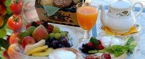 A table with a variety of fruits, vegetables, and a glass of orange juice, along with a teapot and cups. - L'antico Trullo (Fasano)