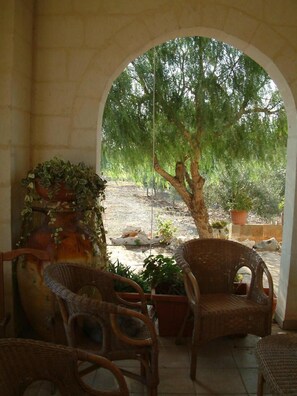 An outdoor seating area with wicker chairs and a large planter with green plants.