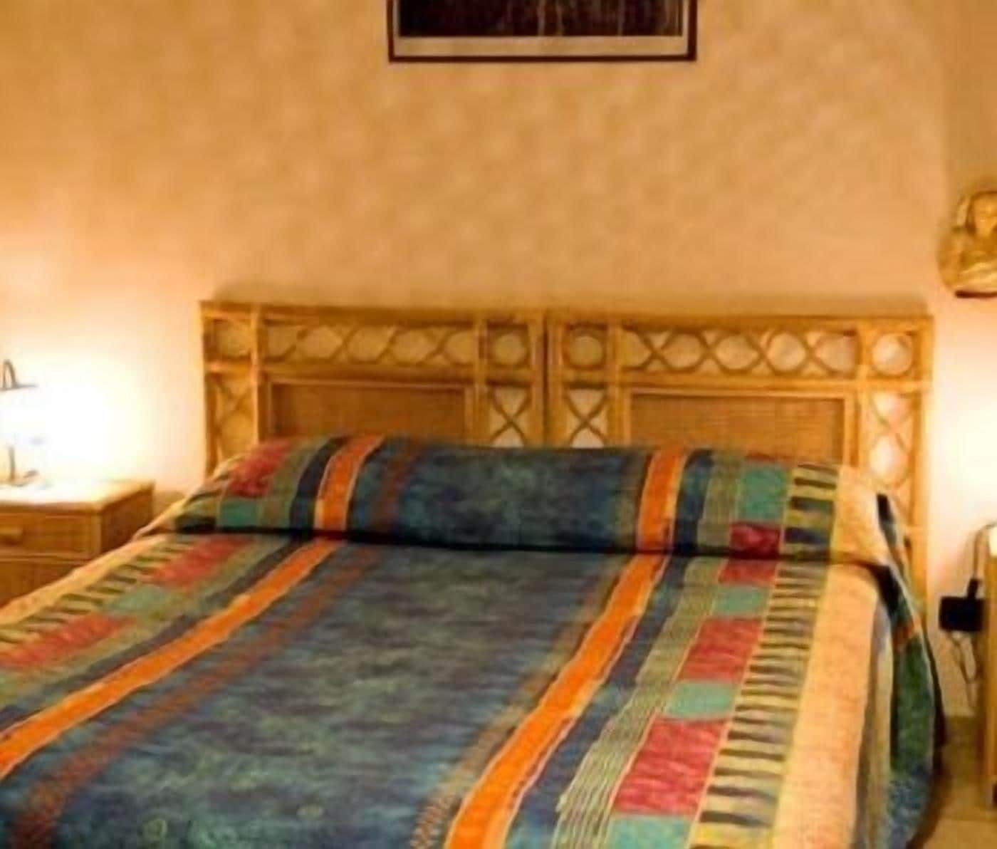 Cama com colcha estampada e cabeceira de madeira.