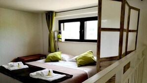 A single bed with a wooden headboard, a bedside table, and a window with curtains. - L'antico Trullo (Fasano)
