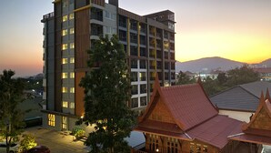 A multi-story building with balconies and a traditional wooden structure in the foreground. - Huahin Terminal (Hua Hin)