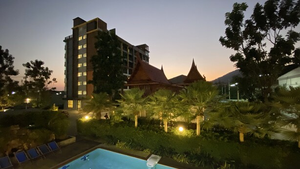 A swimming pool with a view of a hotel and traditional buildings in the background. - Huahin Terminal (Hua Hin)