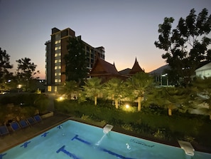 Una piscina con vistas a un hotel y edificios tradicionales al fondo.