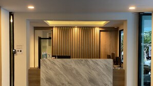 A reception area with a marble counter, wooden paneling, and a ceiling light. - Huahin Terminal (Hua Hin)