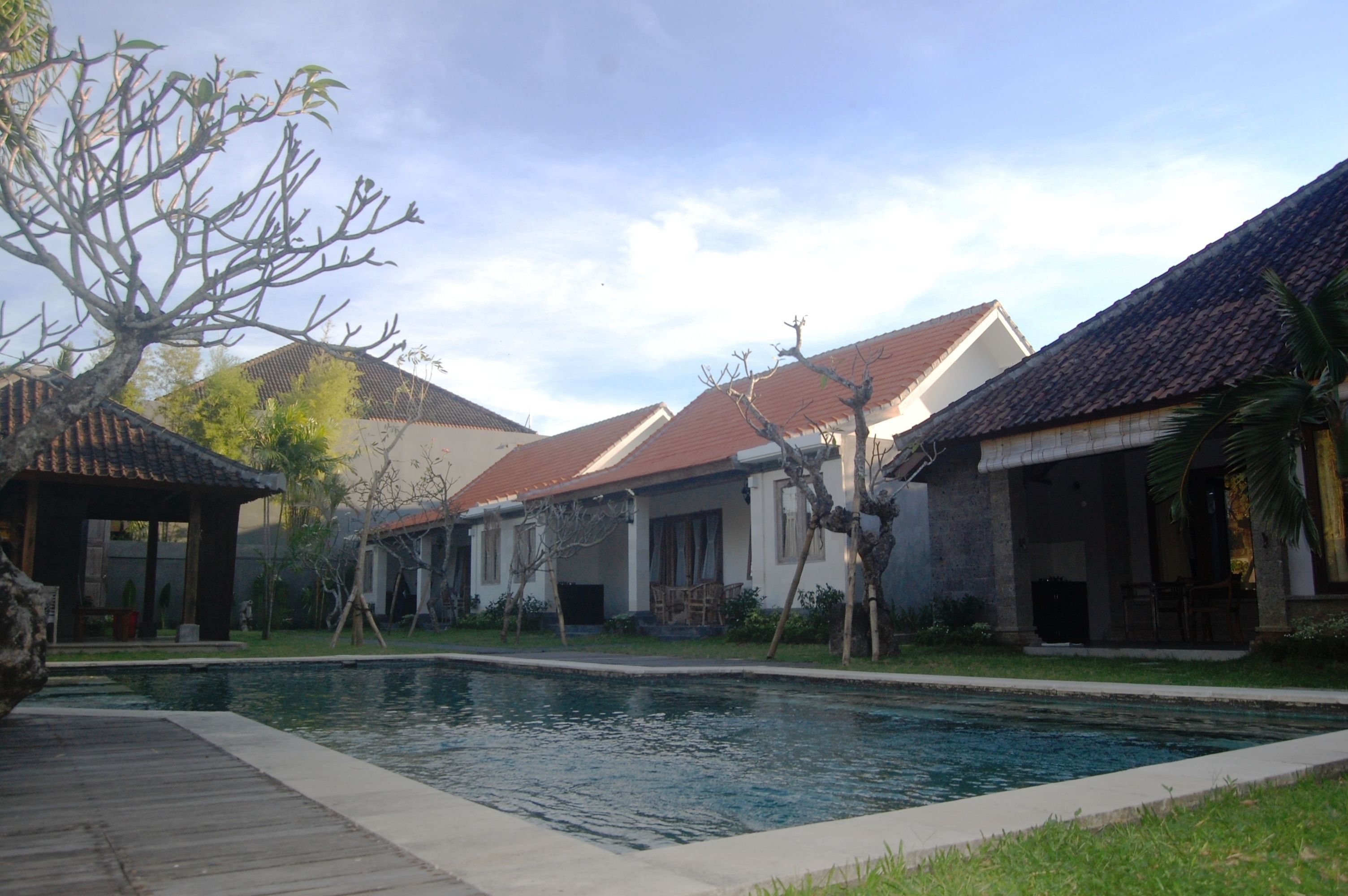 A residential area with a swimming pool, houses with tiled roofs, and a wooden deck.