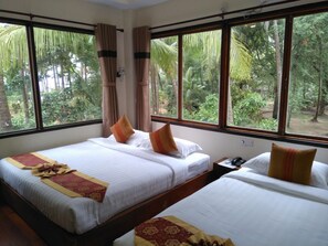 A hotel room with two beds, large windows, and a view of greenery. - Kyaw Myanmar Hotel (Ngapali)