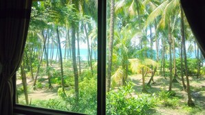 Blick aus dem Fenster auf eine tropische Landschaft mit Palmen und Strand.