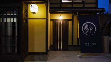 A traditional Japanese building with a lit entrance and a signboard.