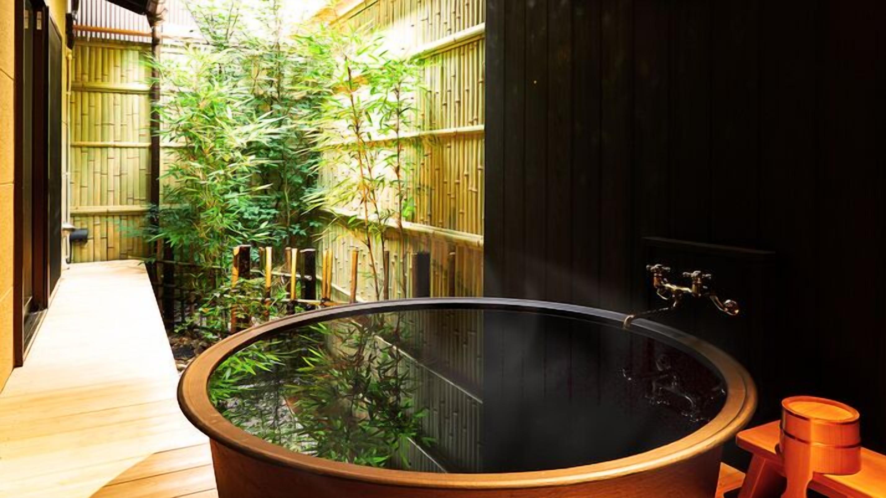 A traditional Japanese onsen with a wooden bath, bamboo surroundings, and a wooden walkway.