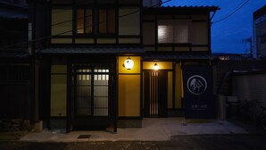 A traditional Japanese building with a wooden gate, a lit entrance, and a sign with Japanese characters.