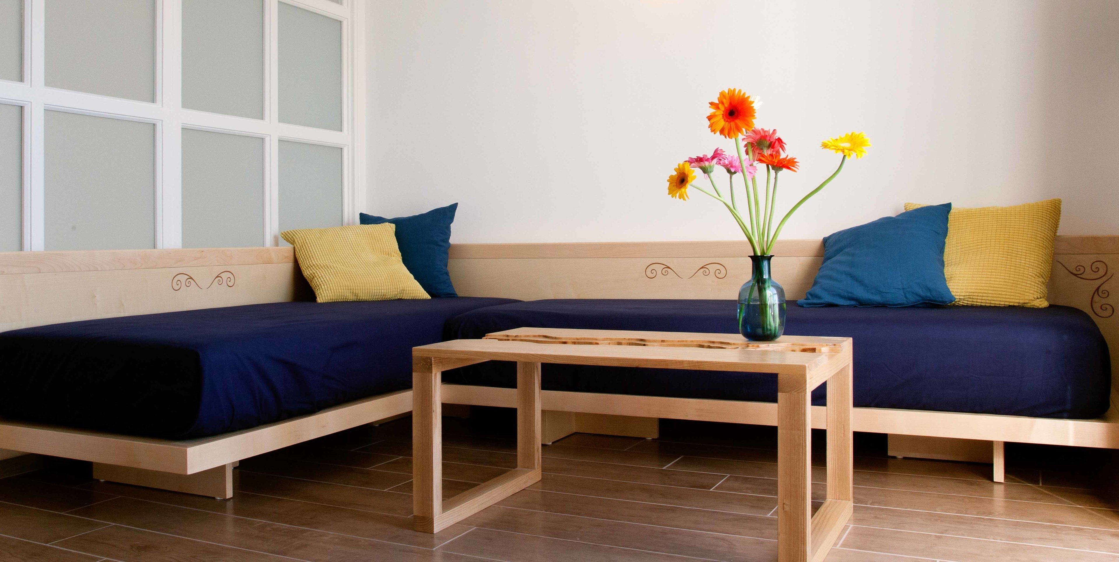 Una sala de estar moderna con dos sofás, una mesa de centro de madera y un jarrón con flores.