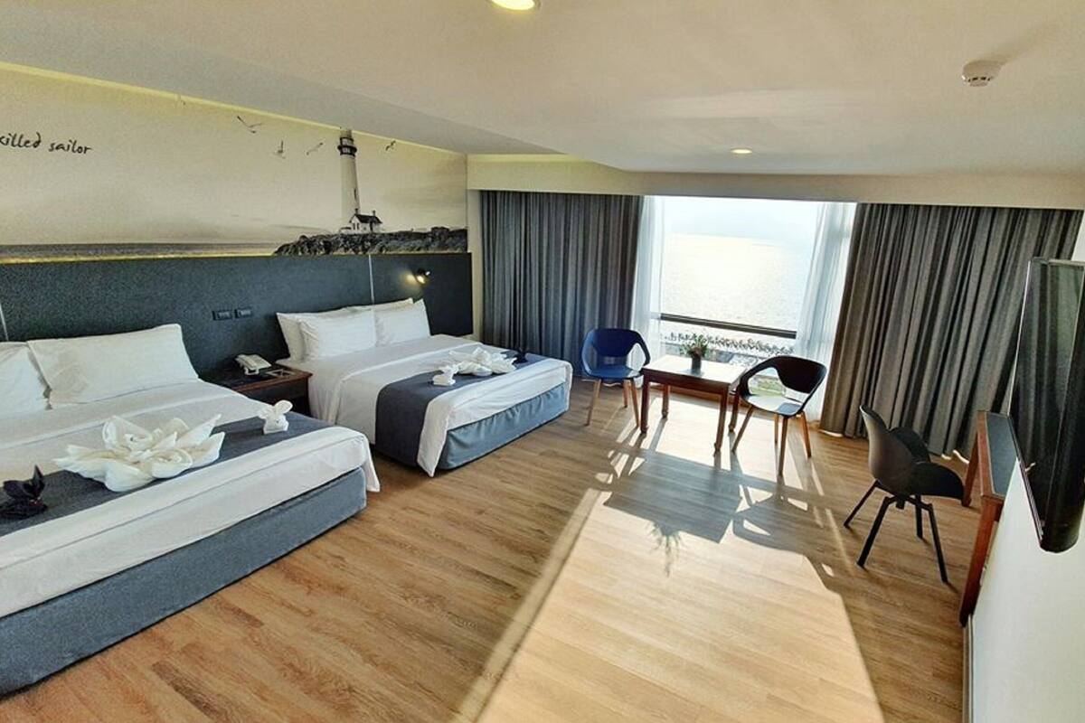 A hotel room with two beds, a desk, a chair, and a TV.