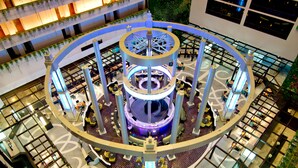 A multi-level atrium with a central circular structure, surrounded by seating areas and a glass ceiling. - Ambassador City Jomtien Pattaya - Ocean Wing (Sattahip)