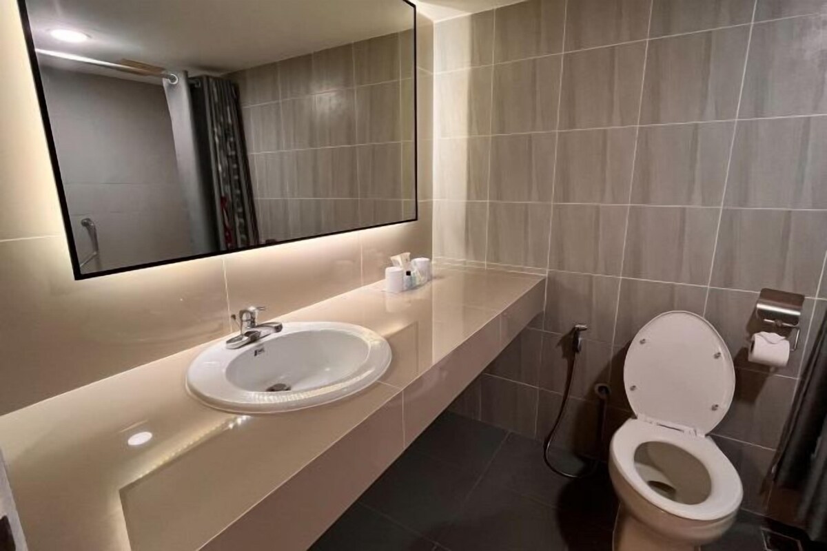 A modern bathroom with a large mirror, a sink, and a toilet.