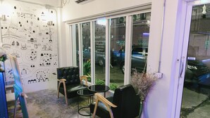 Une pièce dotée d’une porte en verre, de deux fauteuils en cuir noir, d’une petite table ronde et d’un mur orné de diverses illustrations en noir et blanc.