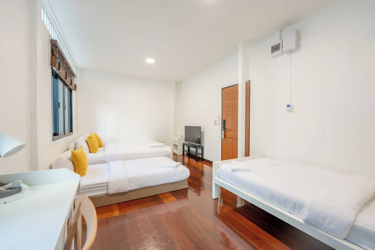 Quarto com duas camas, televisão, escrivaninha e uma cadeira.