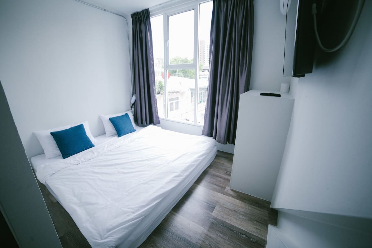 Quarto com uma cama grande, uma televisão e uma janela com cortinas.