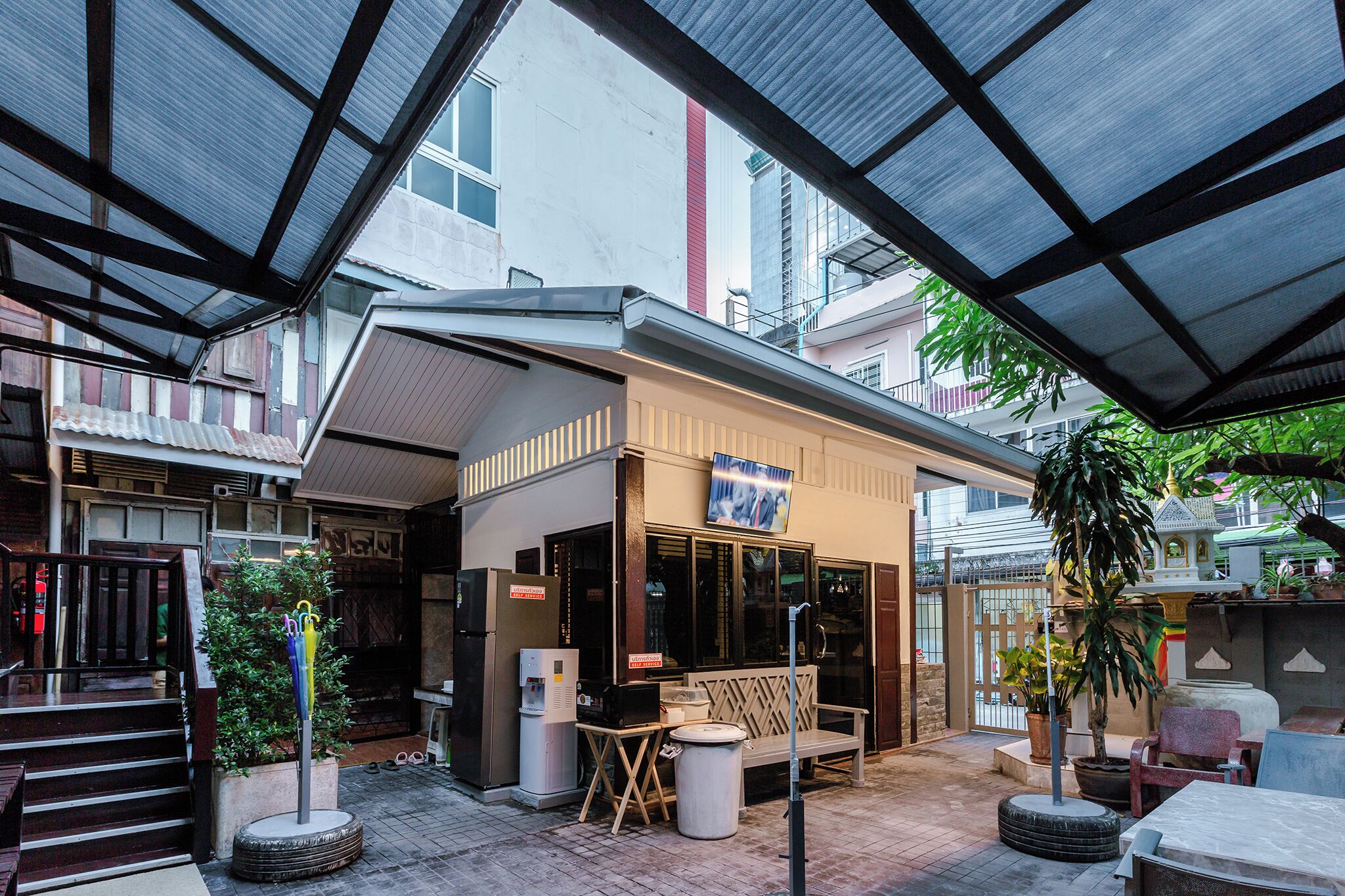 A covered outdoor seating area with a bench, a trash bin, and a small table.