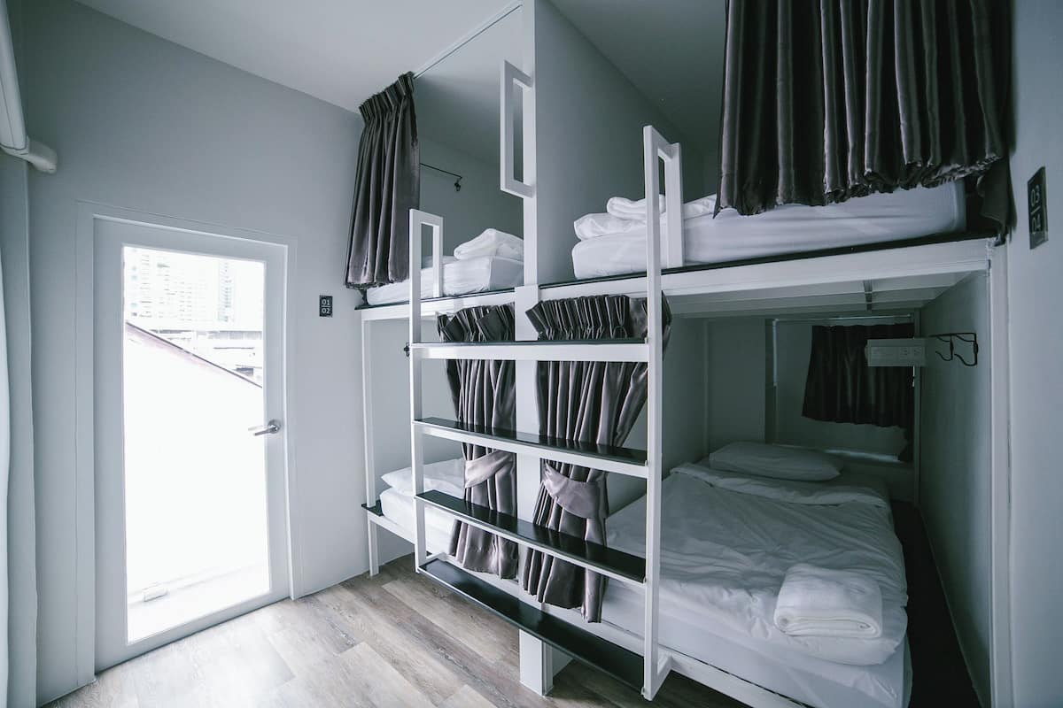 Quarto com beliche, porta branca e vista pela porta.