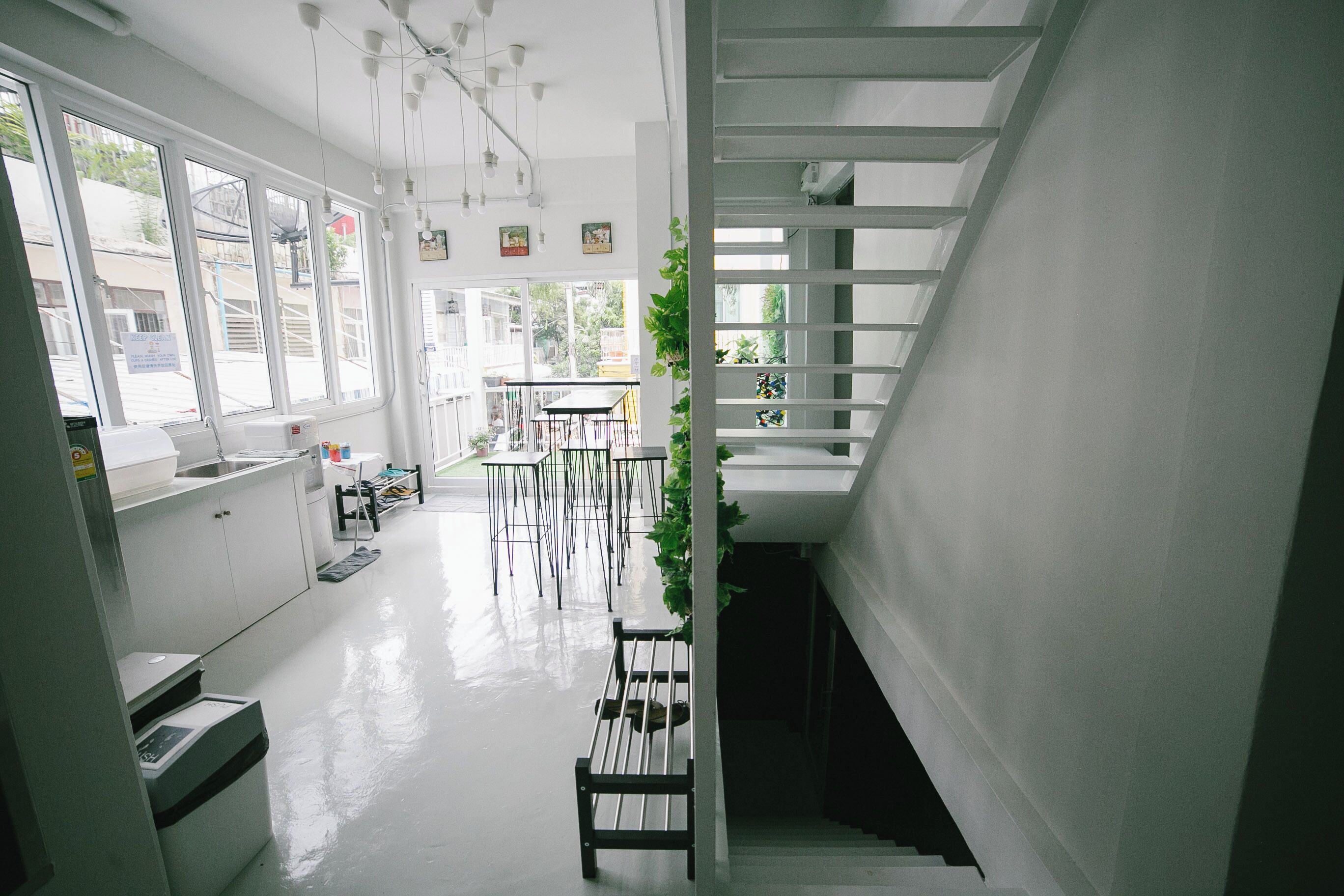 A modern interior with a staircase, white walls, and a dining area with tables and chairs.