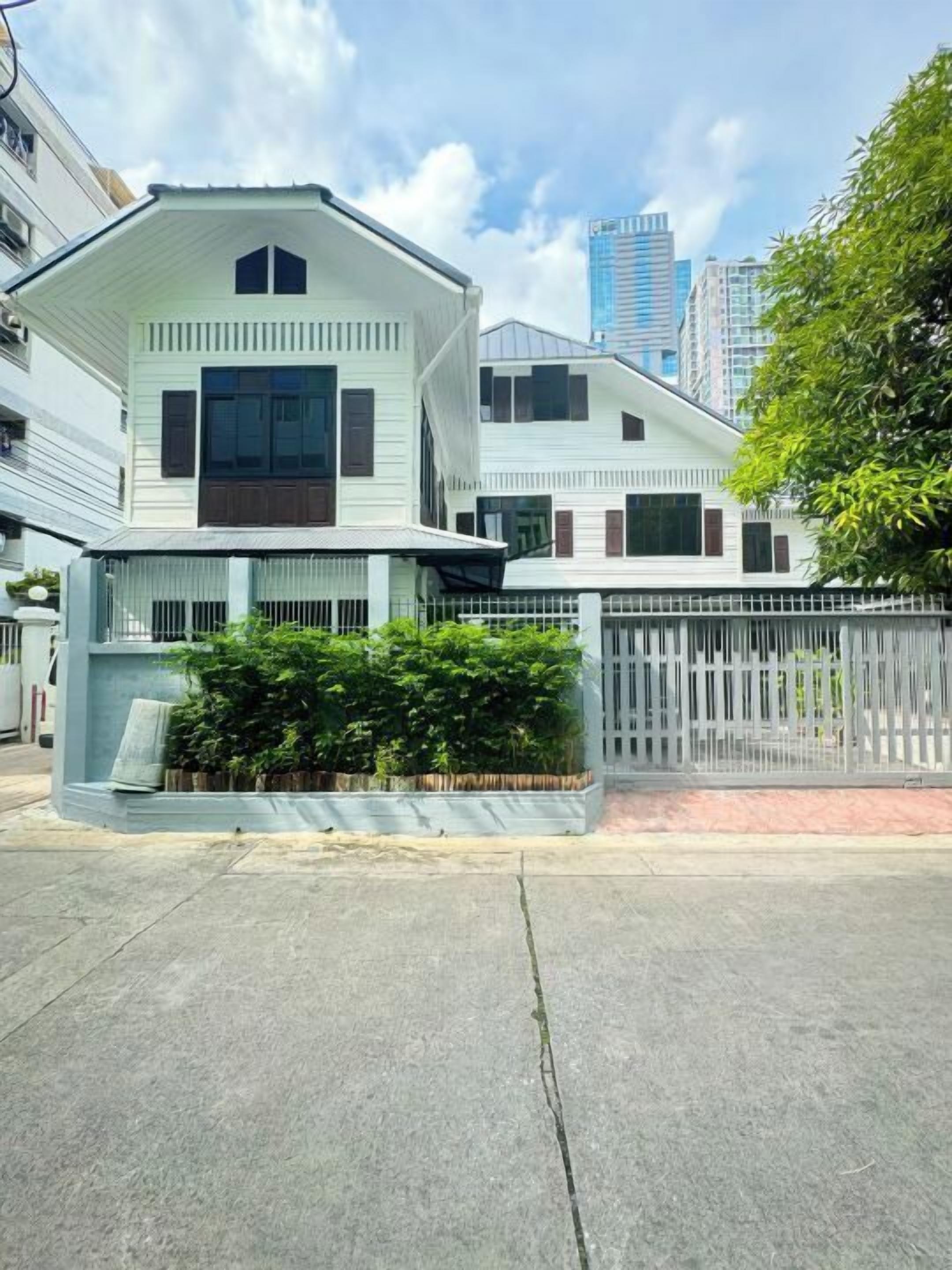 A modern two-story house with a flat roof, large windows, and a gated front yard.