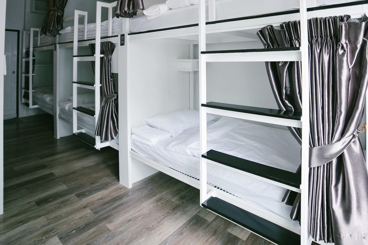 Quarto com beliches, piso de madeira e cortinas.