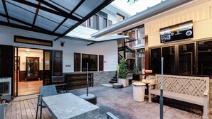 Un espace extérieur aménagé en terrasse, doté d’un coin salon couvert, d’un escalier et d’une devanture de magasin.
