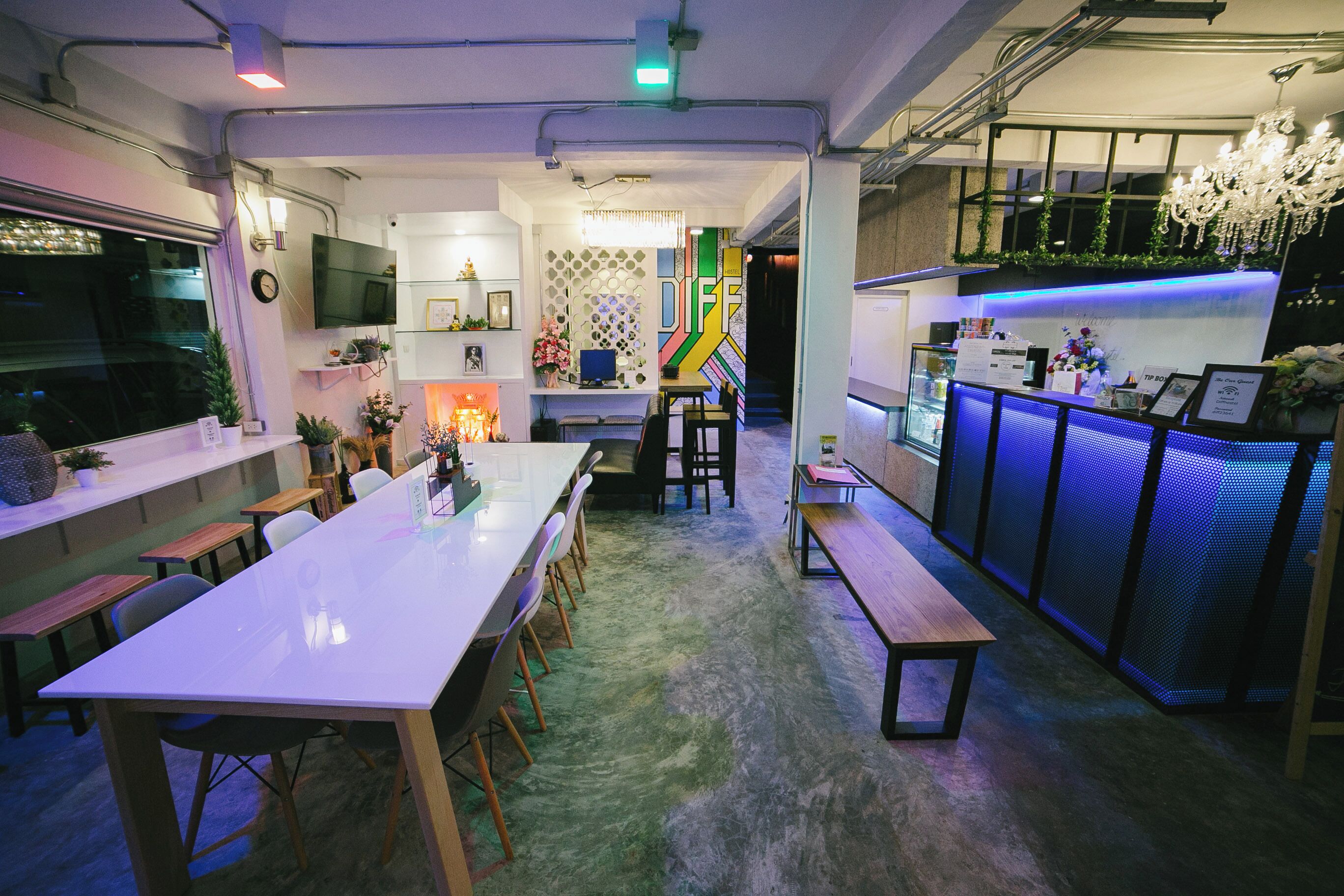 A modern interior with a long dining table, chairs, a bar area, and a staircase leading to an upper level.