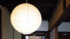 A narrow hallway with a traditional Japanese paper lantern hanging from the ceiling, wooden cabinets, and sliding doors. - Guesthouse Chikayoshi (Kyoto)