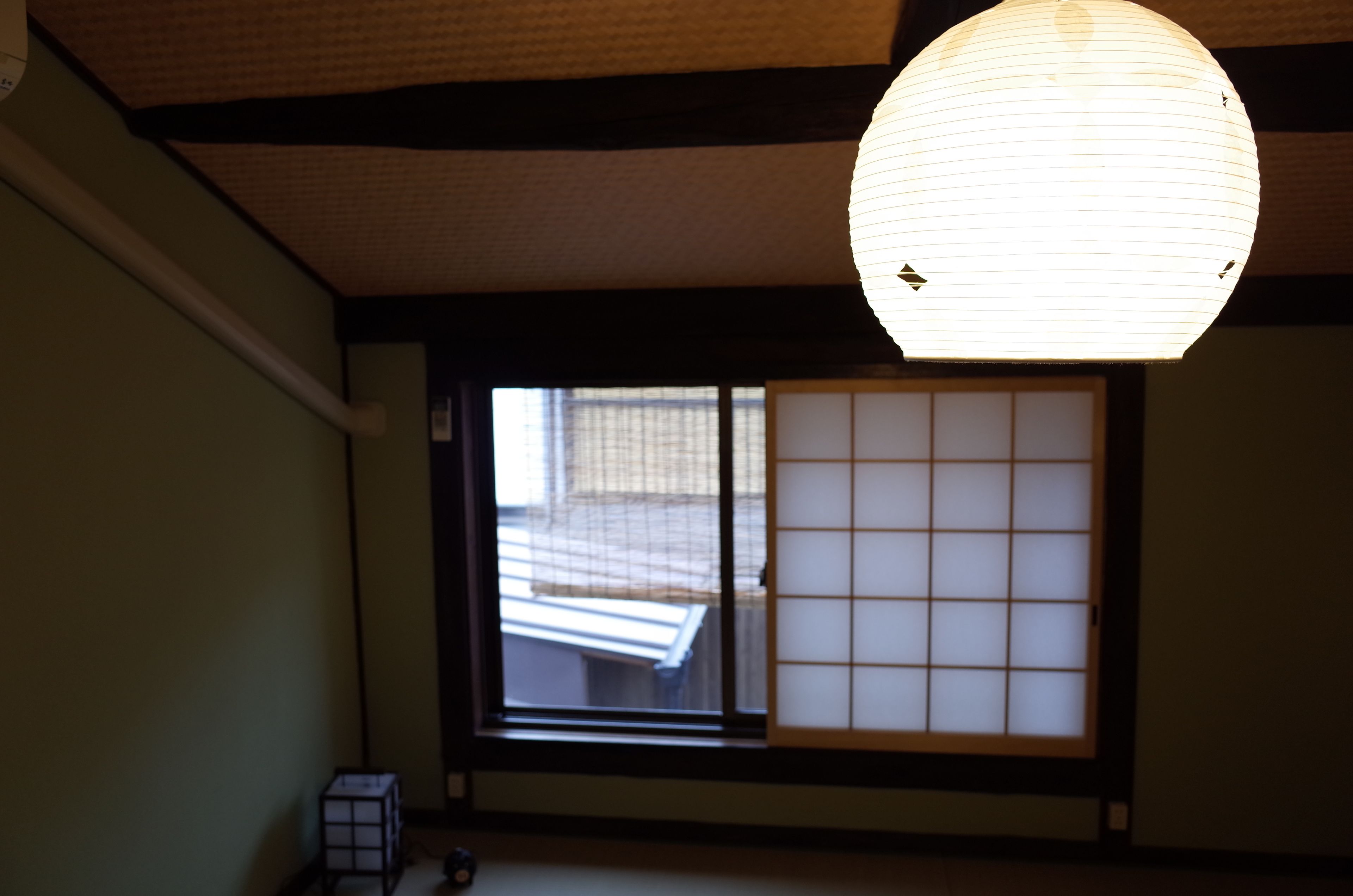 Une pièce de style japonais traditionnel, avec un sol recouvert de tatamis, un paravent shoji et une lanterne en papier suspendue.