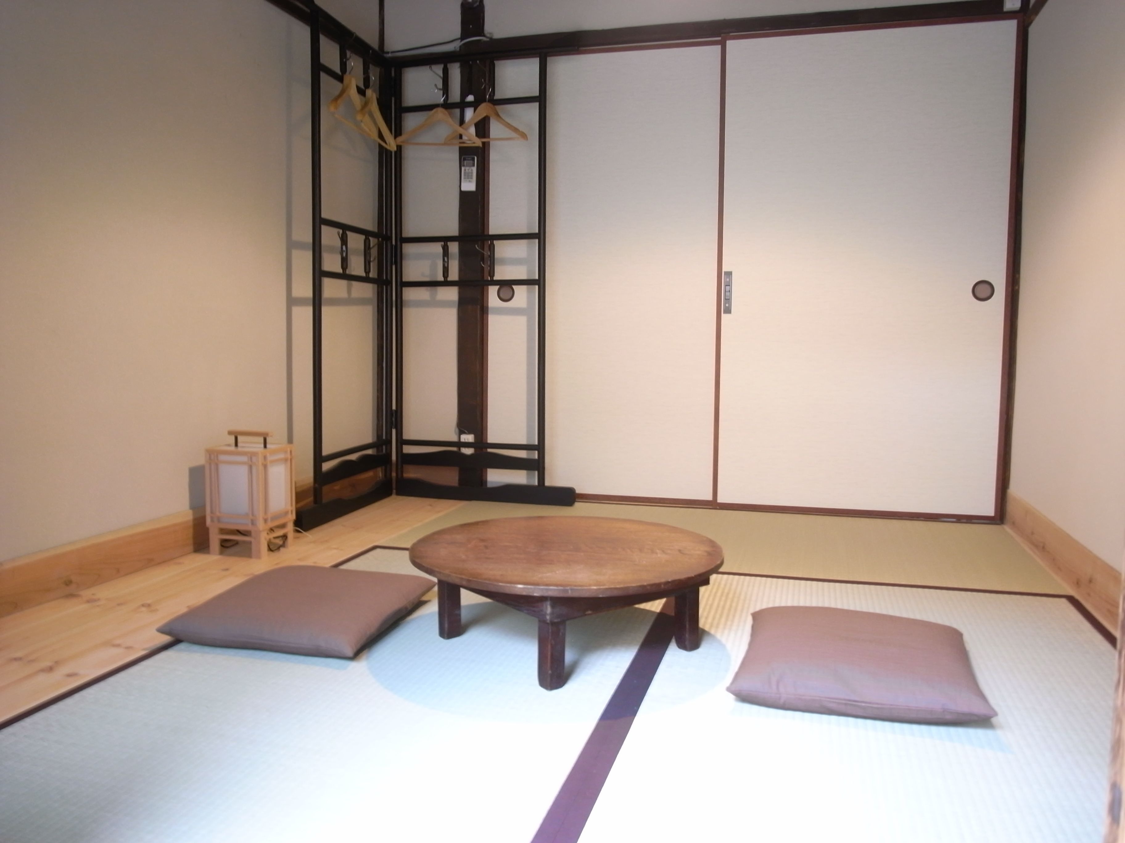 Ett traditionellt japanskt rum med tatamimattor på golvet, ett lågt träbord, kuddar och skjutdörrar.