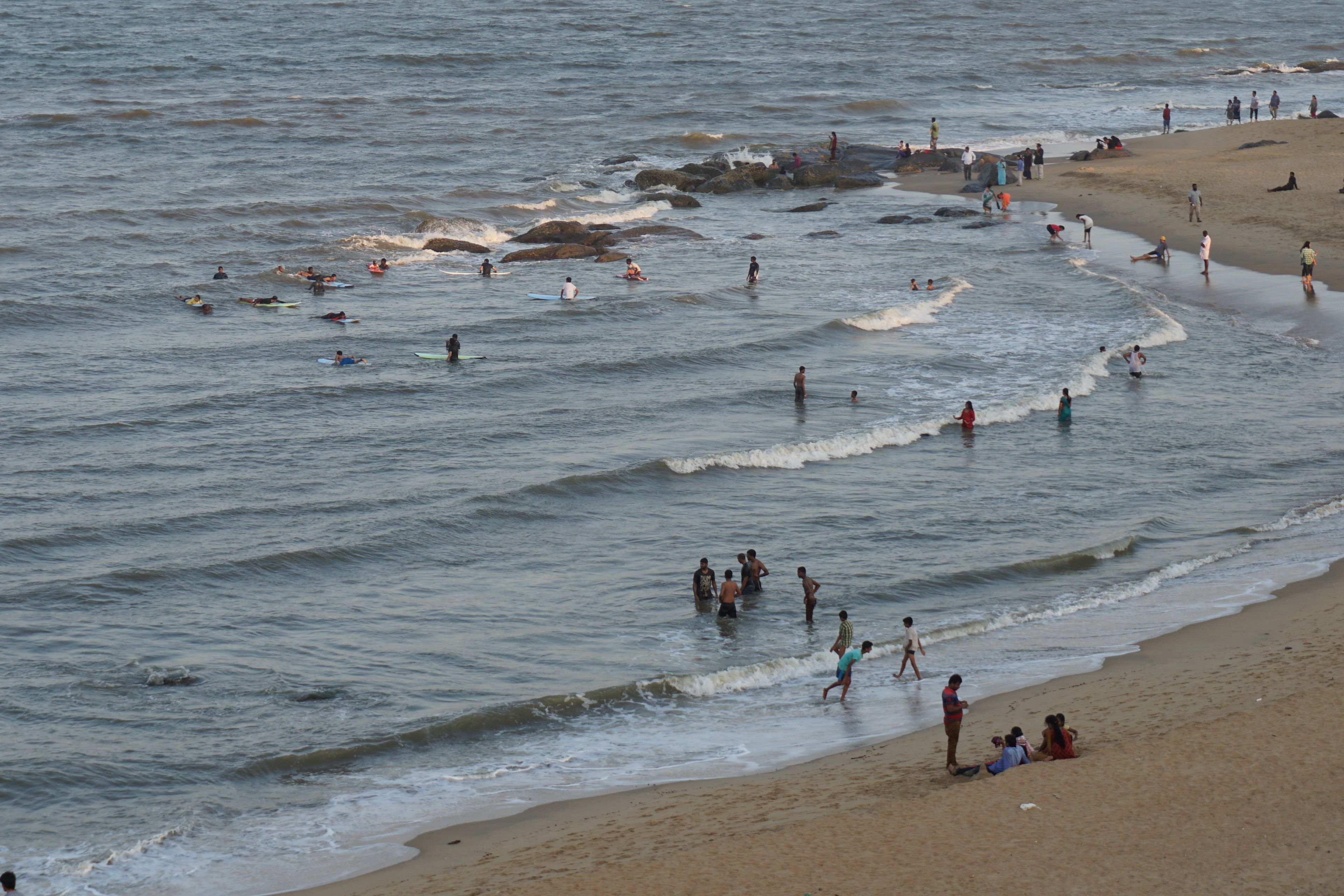 Una playa con gente nadando y practicando surf.