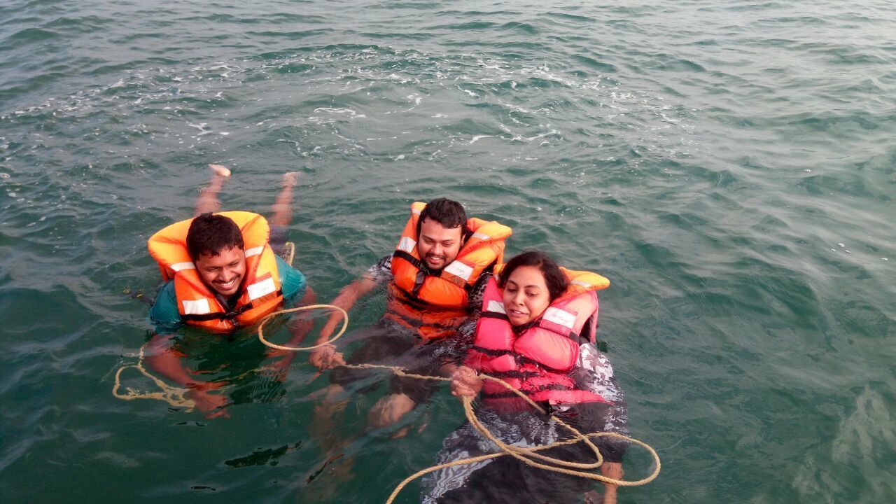 Tres personas en el agua con chalecos salvavidas.