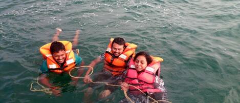 Tres personas en el agua con chalecos salvavidas.