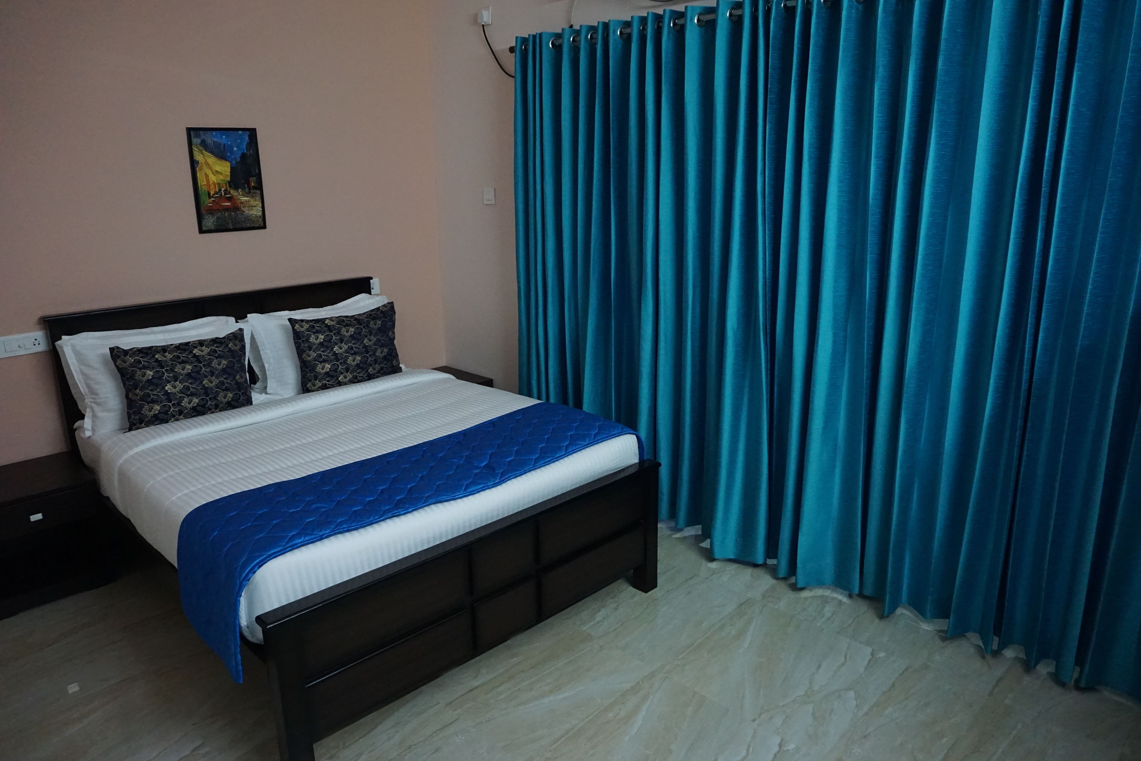 A neatly made bed with a blue quilt, a dark headboard, and two patterned pillows.