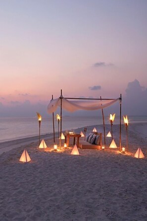 A beach setting with a canopy and seating area, surrounded by torches. - Sea La Vie Covelong Beach Resort (Tirupporur)