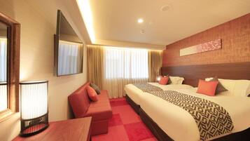 A hotel room with a large bed, a sofa, a desk, and a TV.