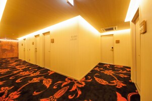 Pasillo de hotel con varias puertas, un suelo estampado y un cartel que indica los números de habitación.
