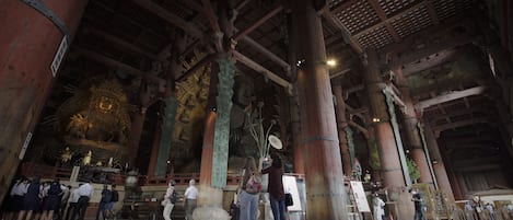 Une vaste structure en bois, dotée de hauts plafonds et de colonnes, qui semble être un bâtiment historique ou culturel.
