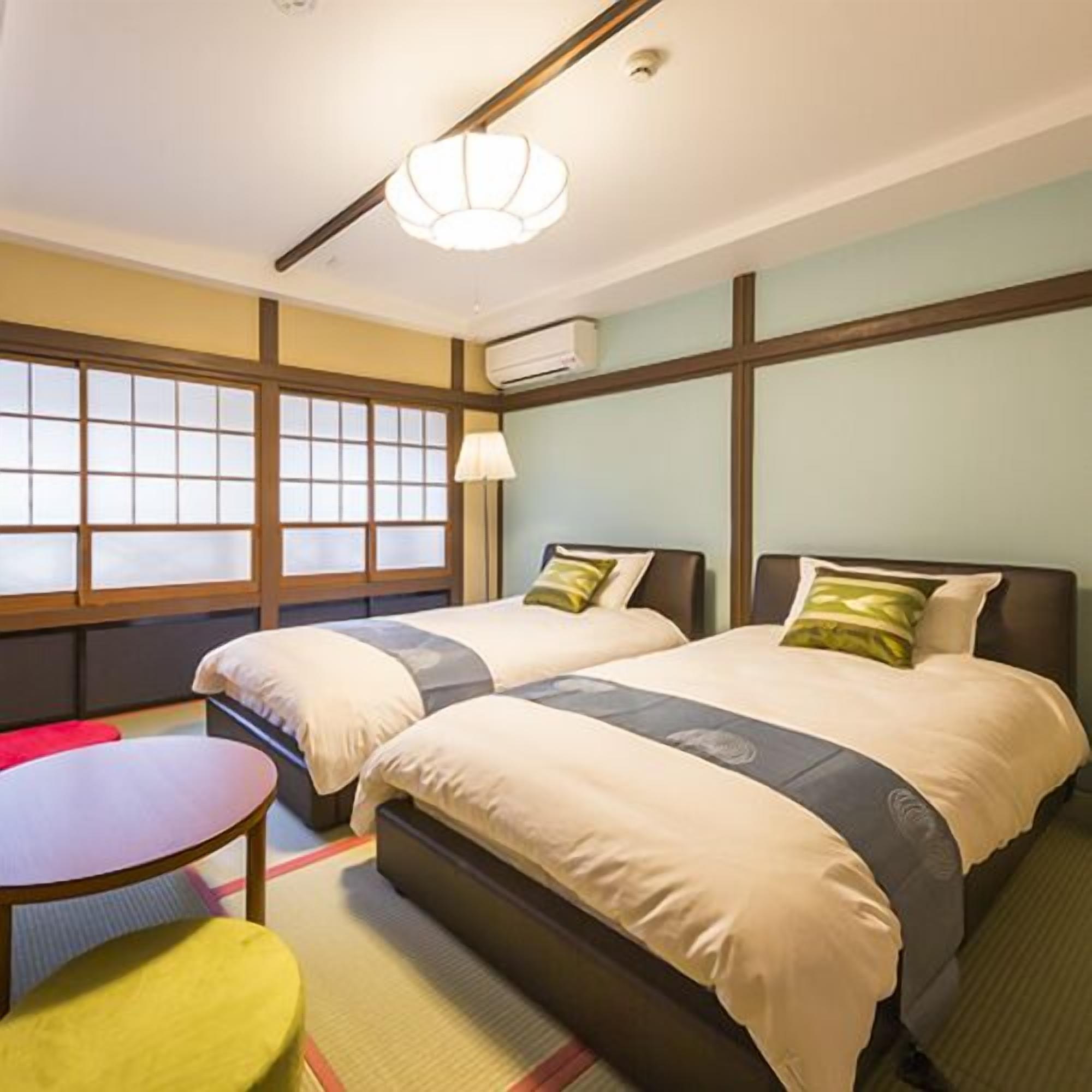 Ein Hotelzimmer mit zwei Betten, einem kleinen Tisch, einem Stuhl und einem Fenster mit Blick.