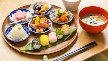 A traditional Japanese meal with various dishes on a wooden tray, including sushi, rice, and soup.