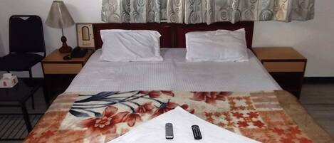 Un letto rifatto con una coperta a fiori, due cuscini e un telecomando sopra.