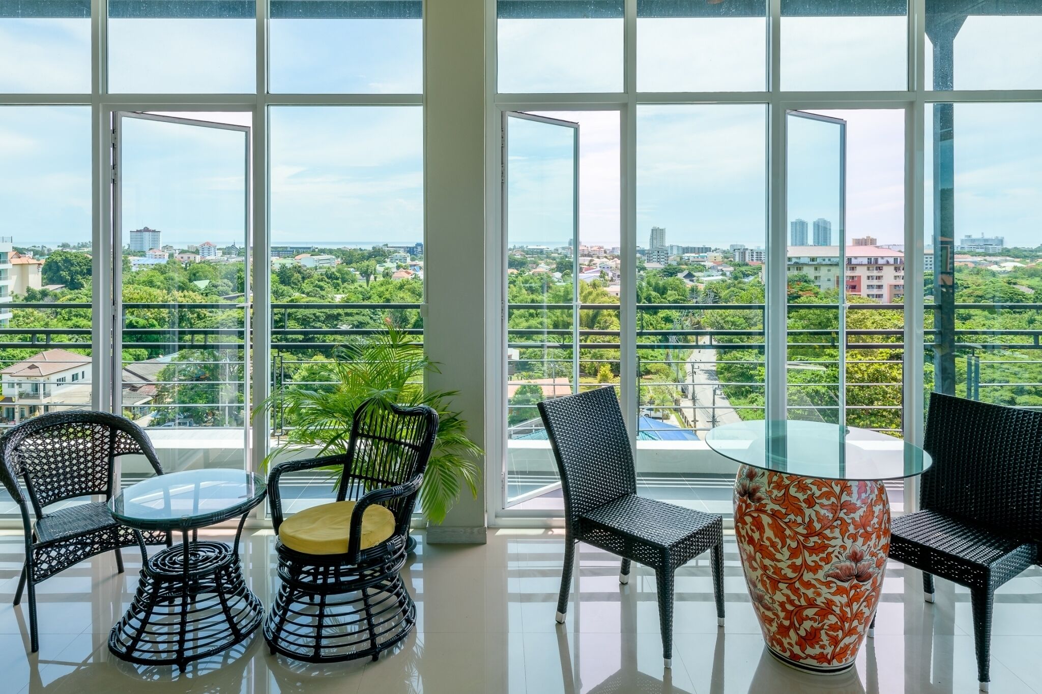 Un balcón amplio con ventanas grandes, que ofrece vistas a un paisaje urbano y zonas verdes.
